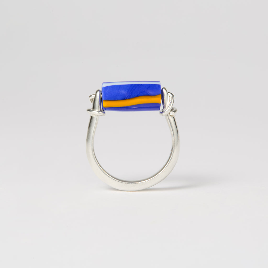 Sterling silver and glass kinetic ring with deep blue bead featuring white and yellow stripes