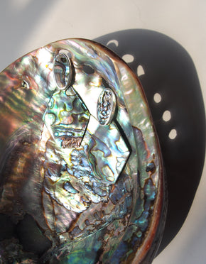 abalone stud earrings resting on abalone shell